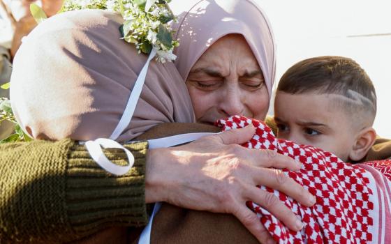 Woman's face crinkles with emotion as she embrace other woman and young boy.